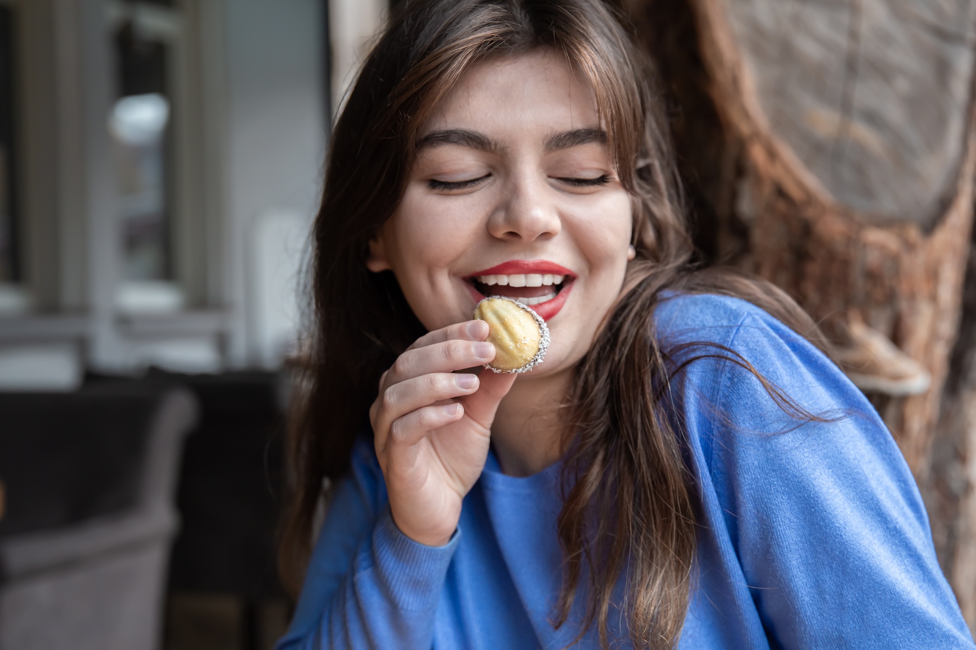 A young woman eating walnut-shaped shortbread sandwich cookies.